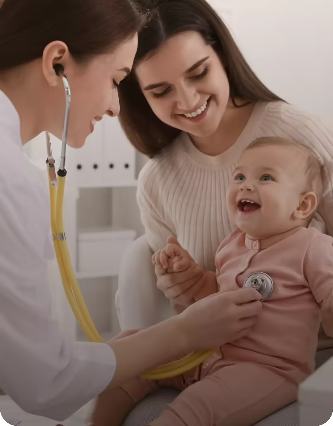 Pediatra examinando um bebê no colo da mãe durante a consulta